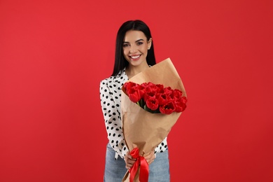 Happy woman with tulip bouquet on red background. 8th of March celebration