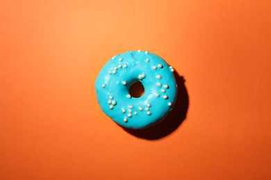 Photo of Delicious glazed doughnut on orange background, top view