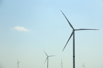 Photo of Modern wind turbines against blue sky. Energy efficiency