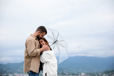 Photo of Young couple with umbrella enjoying time together under rain outdoors, space for text