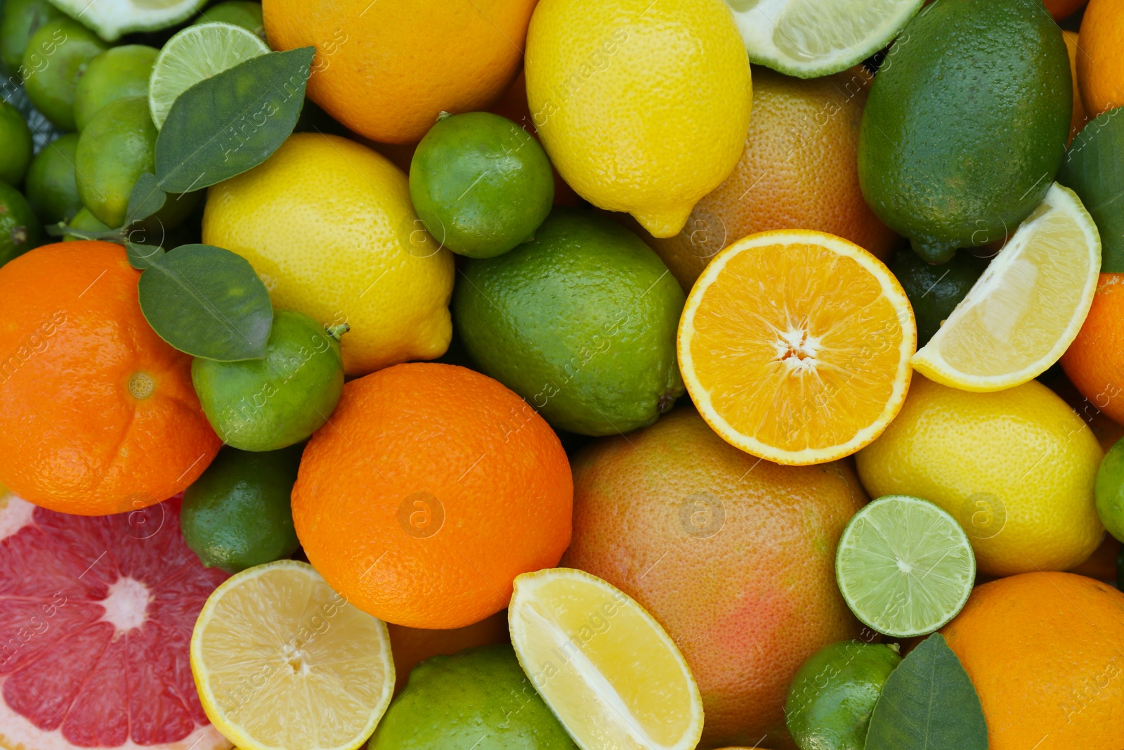 Photo of Different fresh citrus fruits and leaves as background, top view.