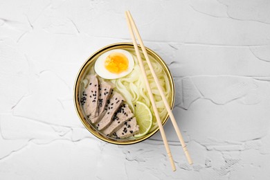 Photo of Bowldelicious rice noodle soup with meat and egg on white textured table, top view