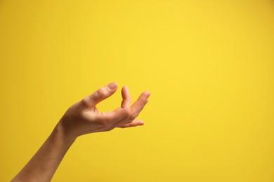 Woman holding something in hand on yellow background, closeup. Space for text