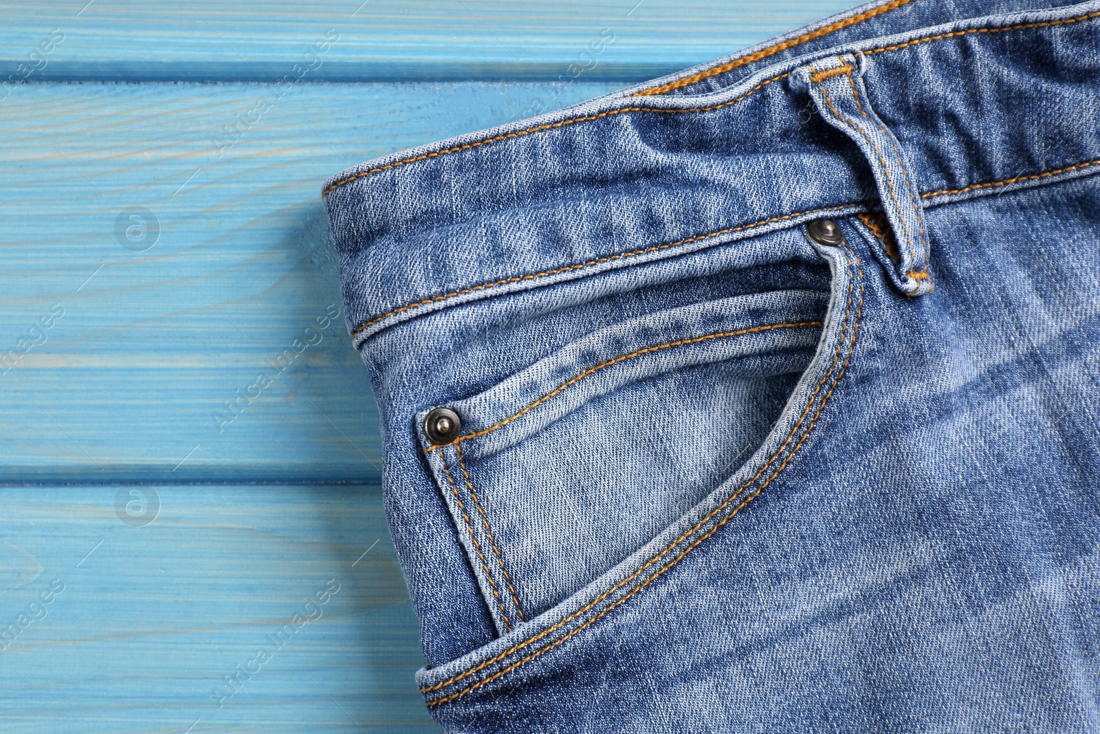 Photo of Stylish blue jeans on wooden background, closeup of inset pocket