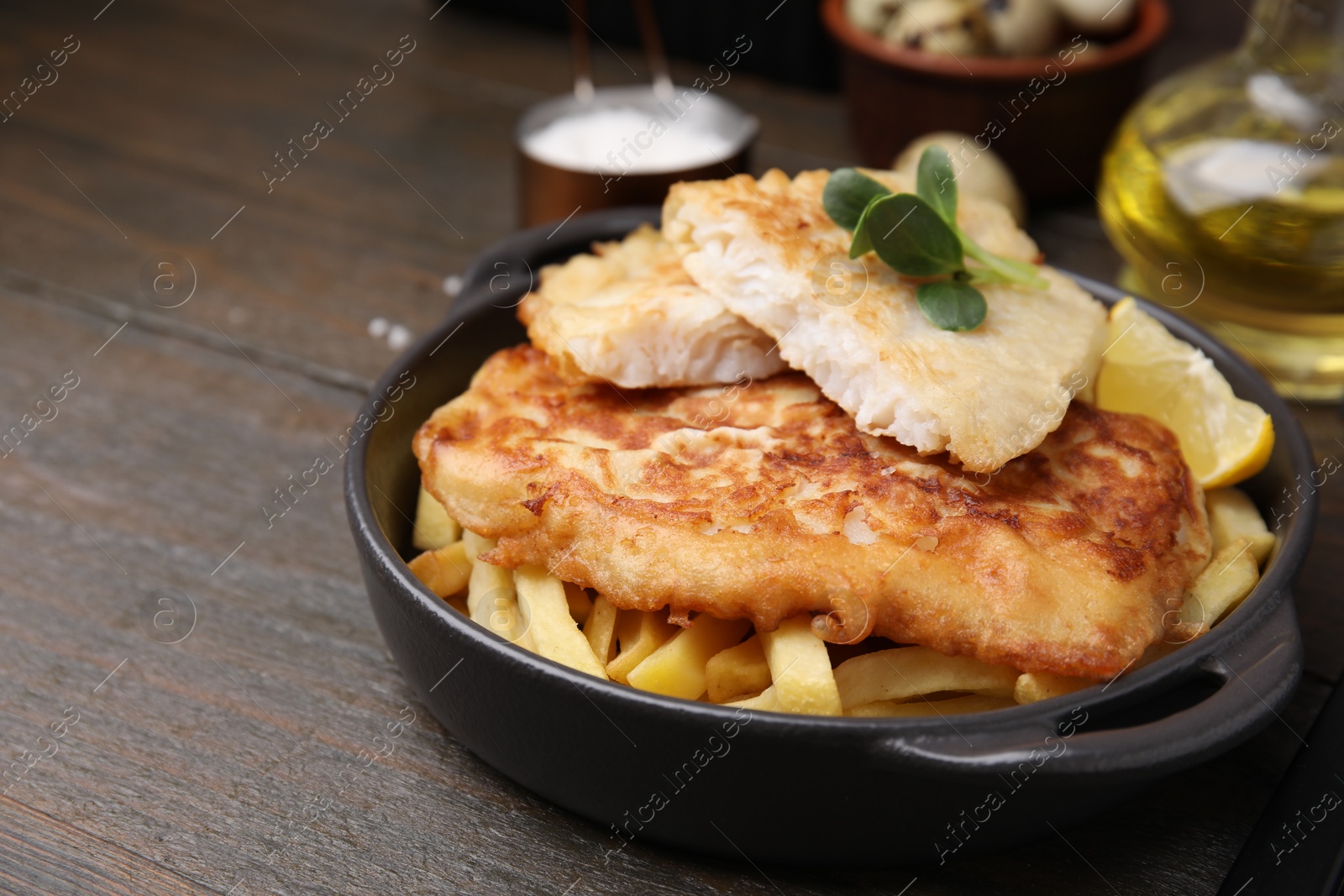 Photo of Tasty soda water battered fish, potato chips and lemon slice on wooden table, space for text