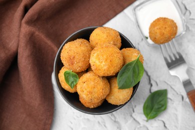 Photo of Bowl of delicious fried tofu balls with basil on white textured table, flat lay