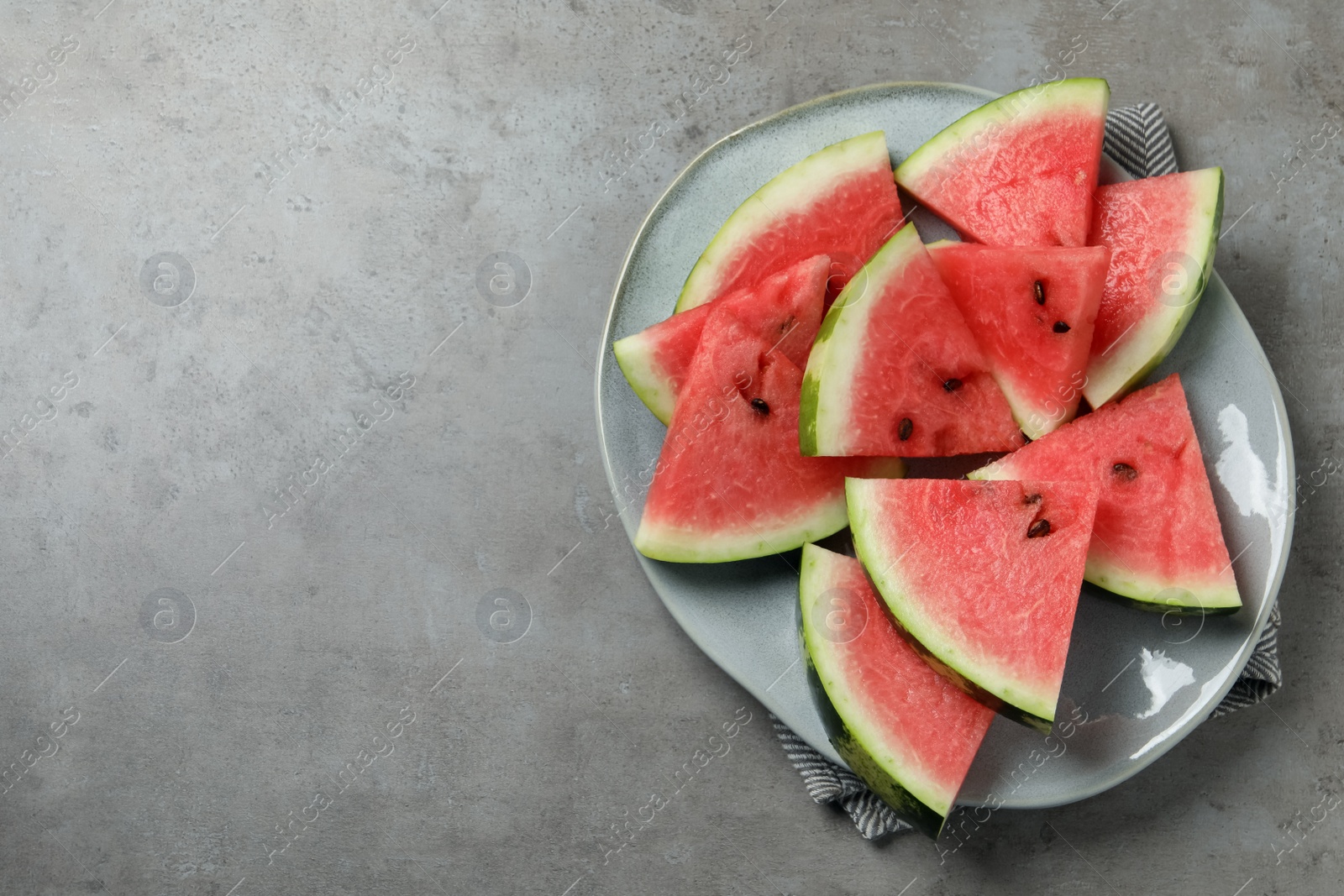 Photo of Delicious fresh watermelon slices on grey table, top view. Space for text