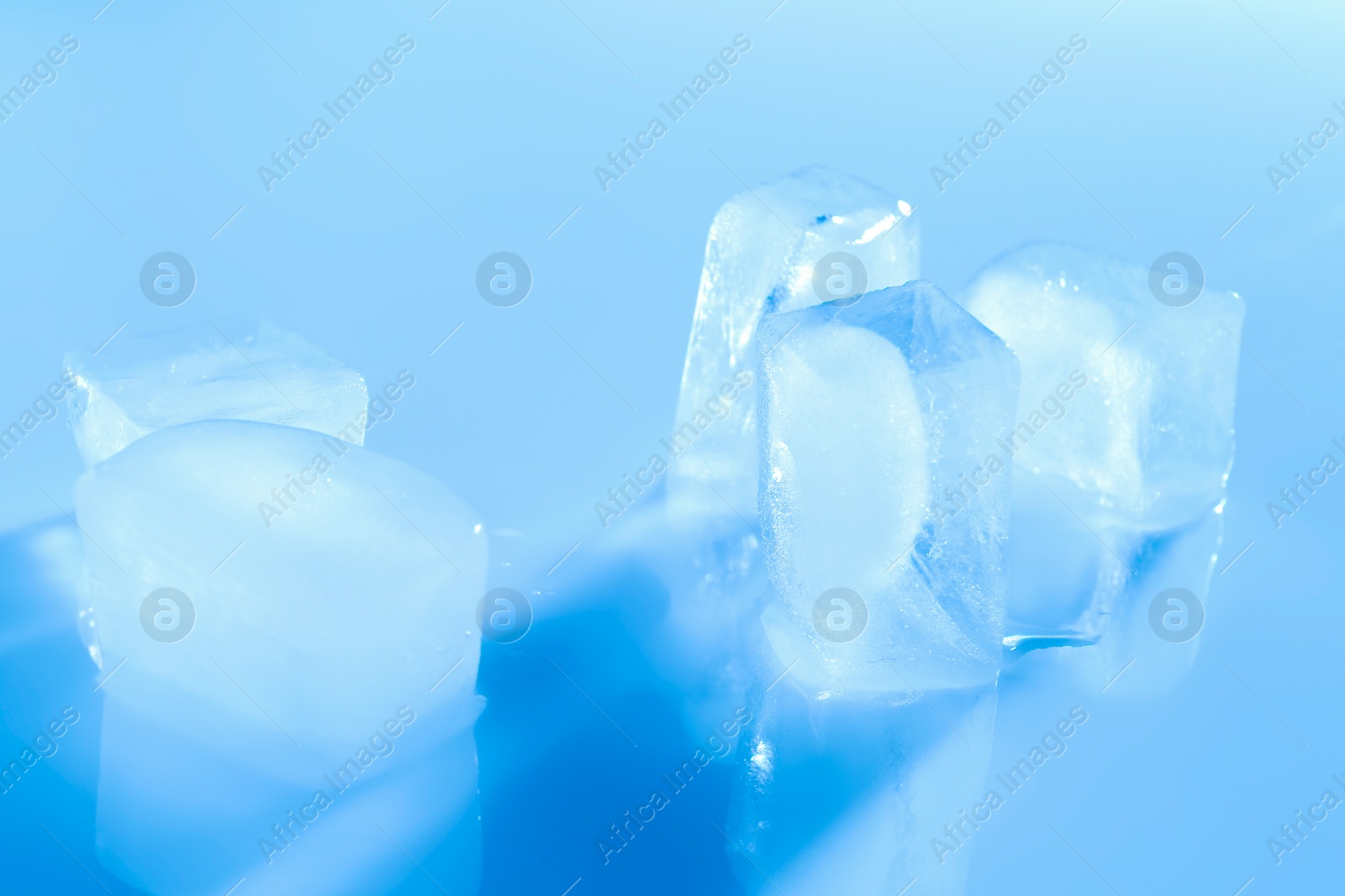 Photo of Melting ice cubes on color background. Frozen liquid