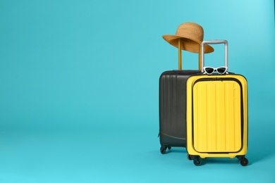 Photo of Stylish suitcases with hat and sunglasses on color background. Space for text