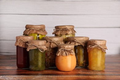 Photo of Many jars with different preserved ingredients on wooden table