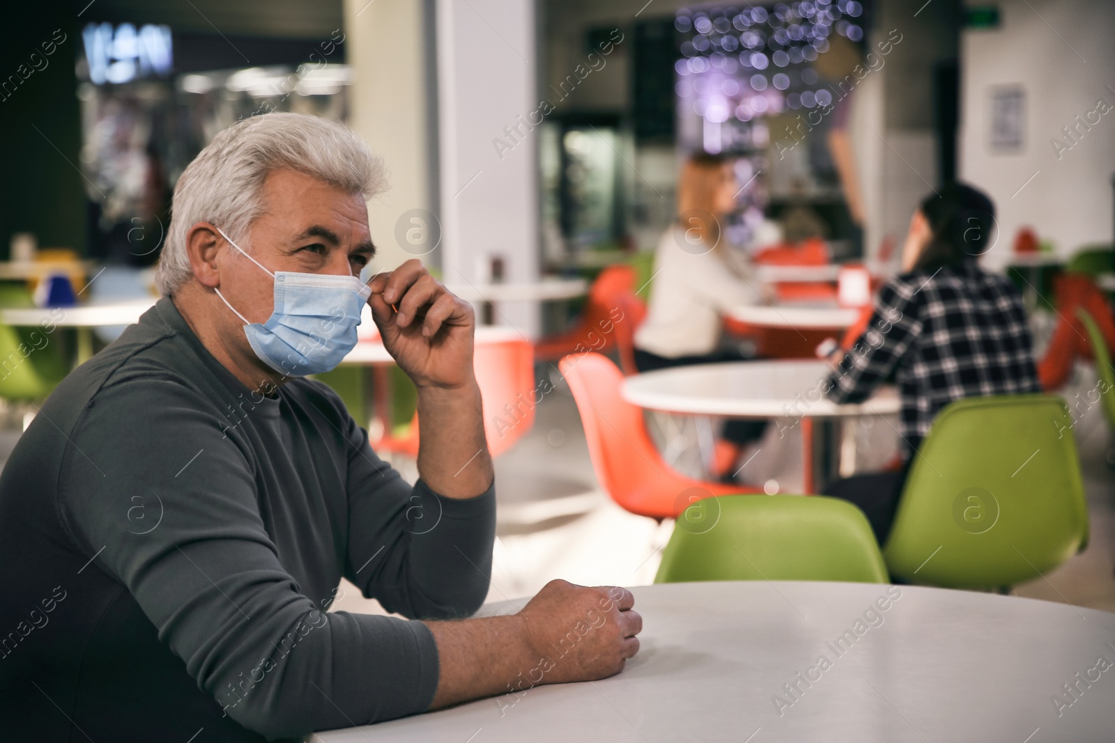 Photo of Senior man with medical mask in cafe. Virus protection