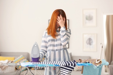 Photo of Tired housewife ironing clothes at home