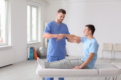 Photo of Physiotherapist working with male patient in clinic