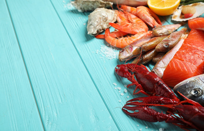 Photo of Fresh fish and different seafood on blue wooden table. Space for text