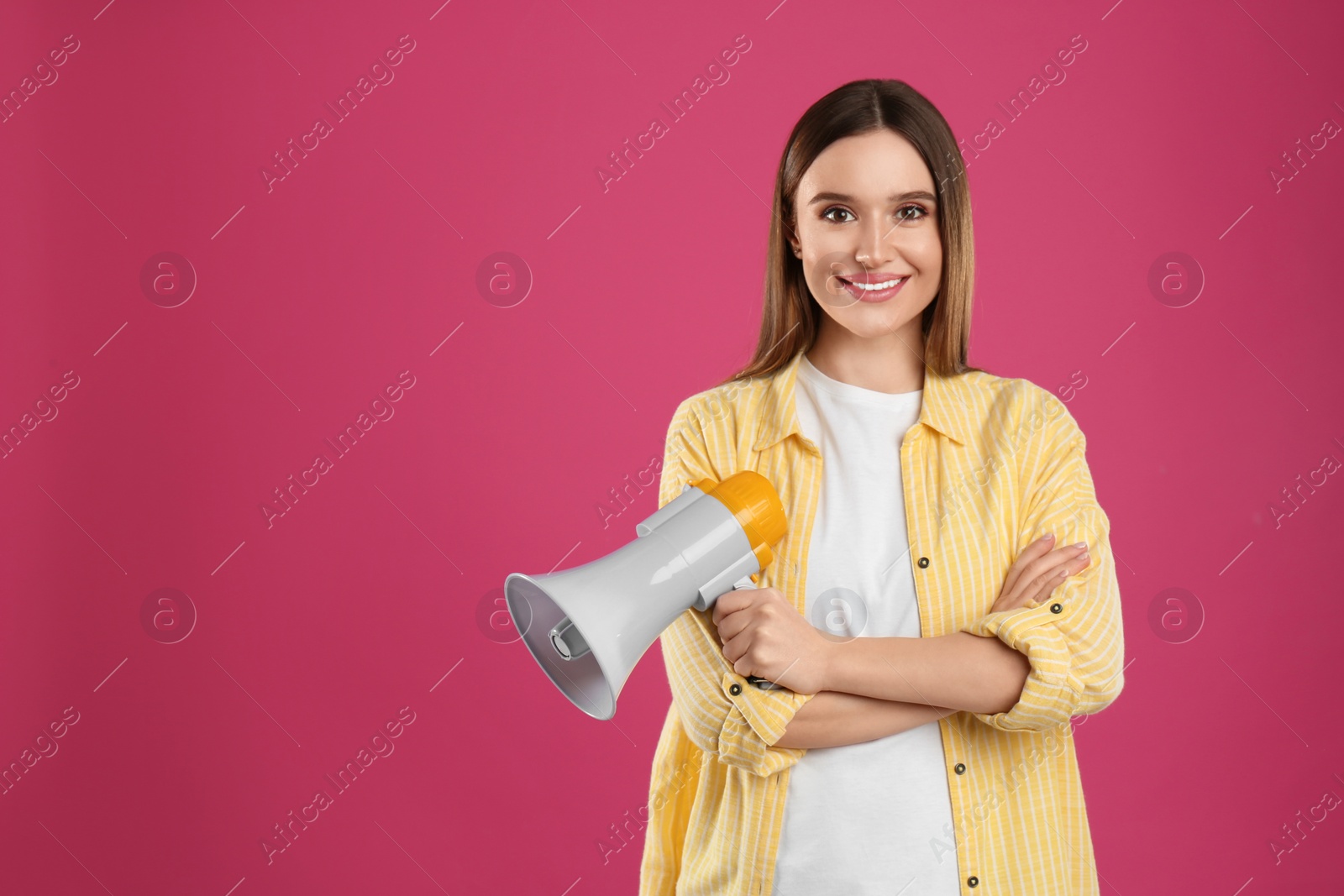 Photo of Young woman with megaphone on pink background. Space for text