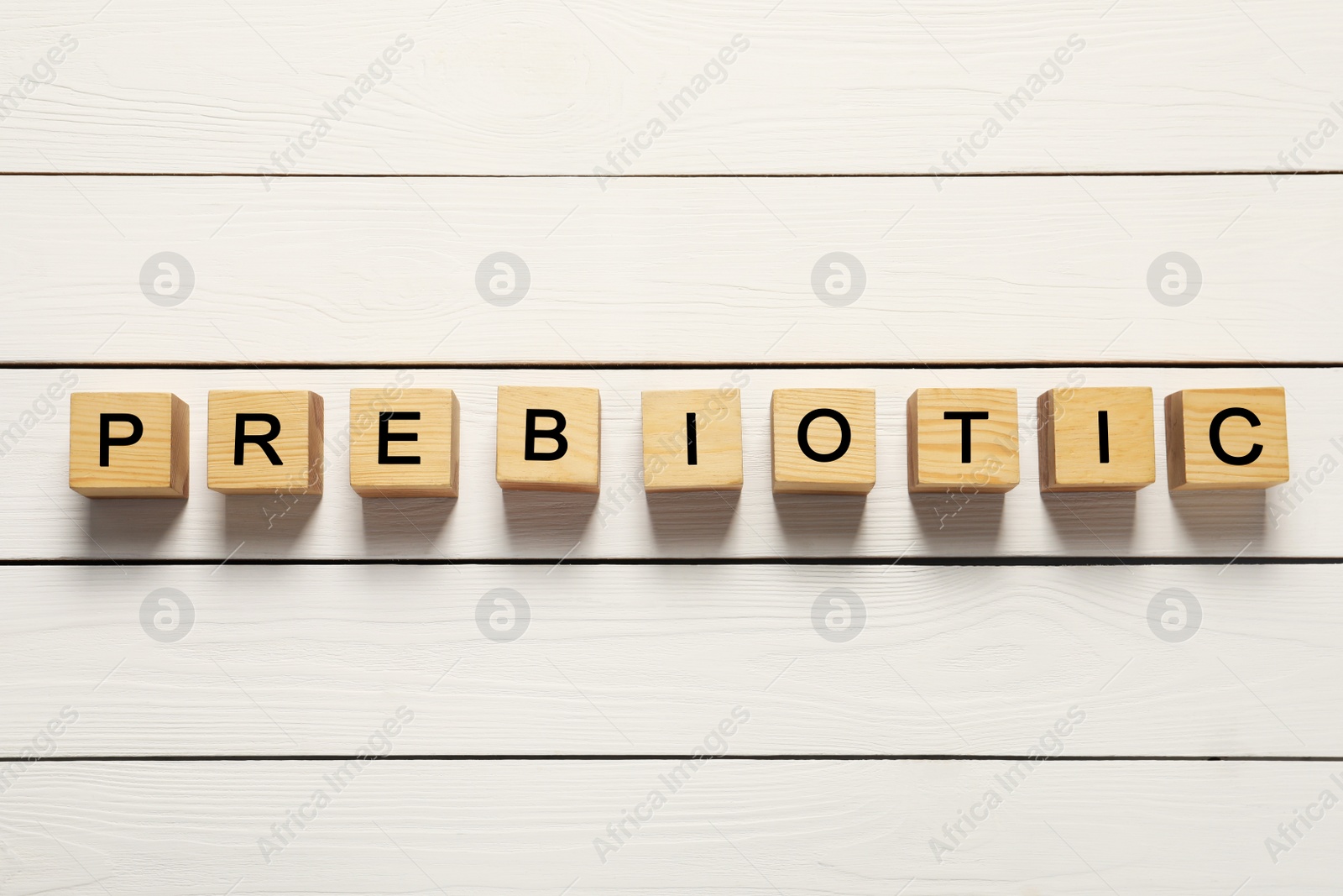 Photo of Wooden cubes with word Prebiotic on white table, flat lay