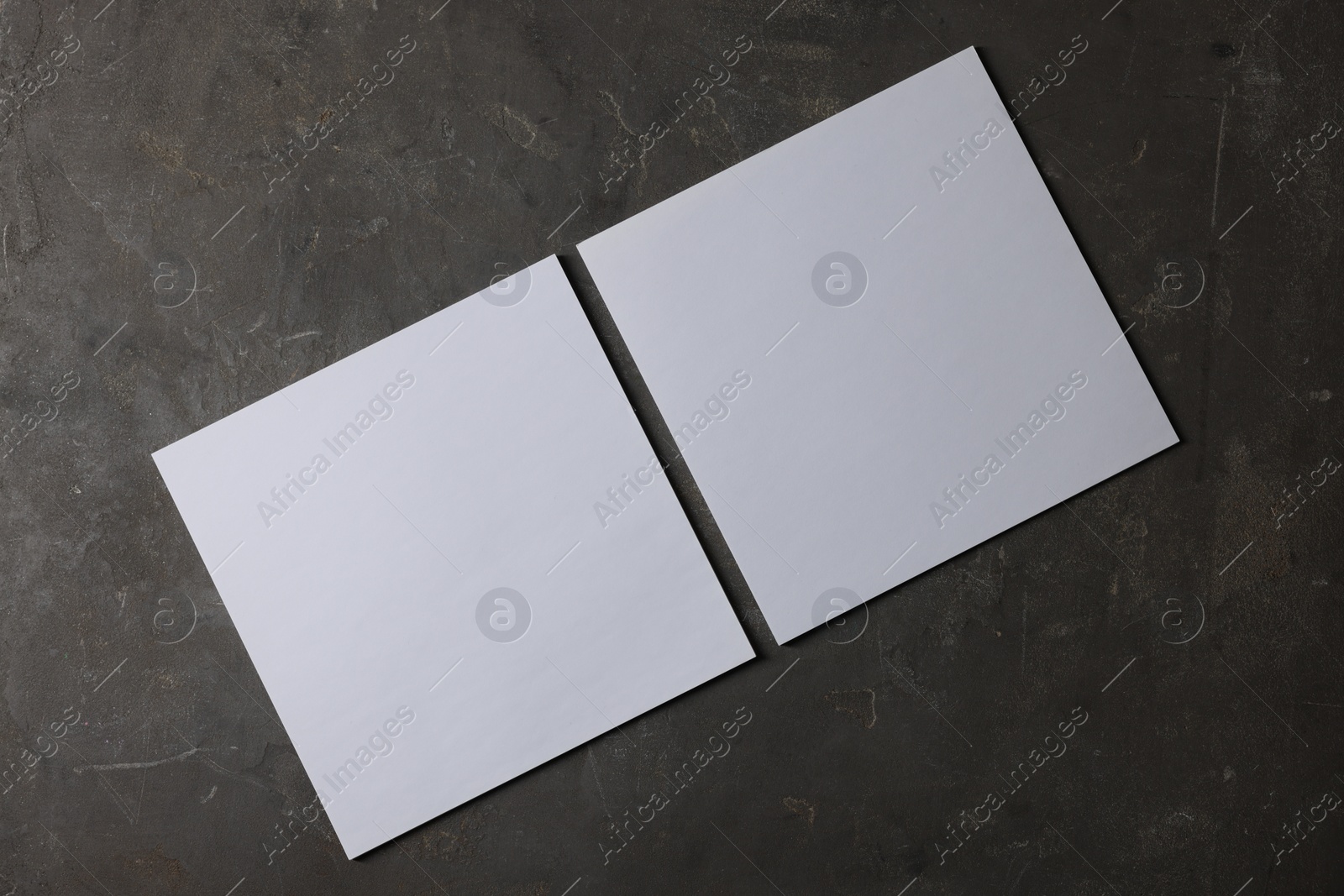 Photo of Blank paper sheets on dark textured background, top view. Mockup for design