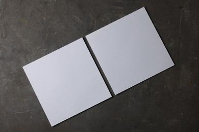 Photo of Blank paper sheets on dark textured background, top view. Mockup for design