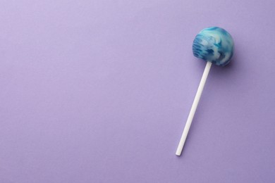 Tasty lollipop on violet background, top view. Space for text