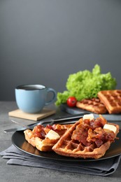 Tasty Belgian waffles served with bacon, butter and coffee on grey table. Space for text