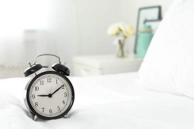 Photo of Alarm clock on bed. Time to wake up