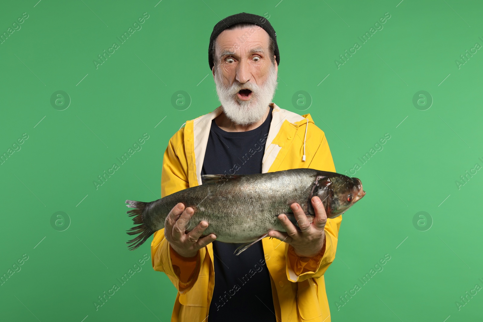 Photo of Shocked fisherman with caught fish on green background