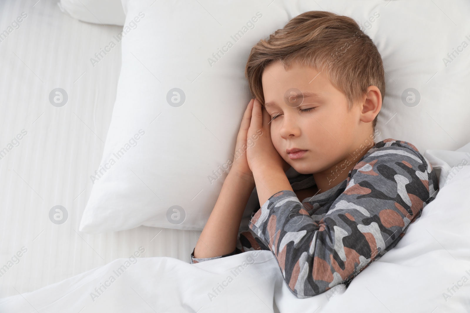 Photo of Cute boy sleeping in bed, above view