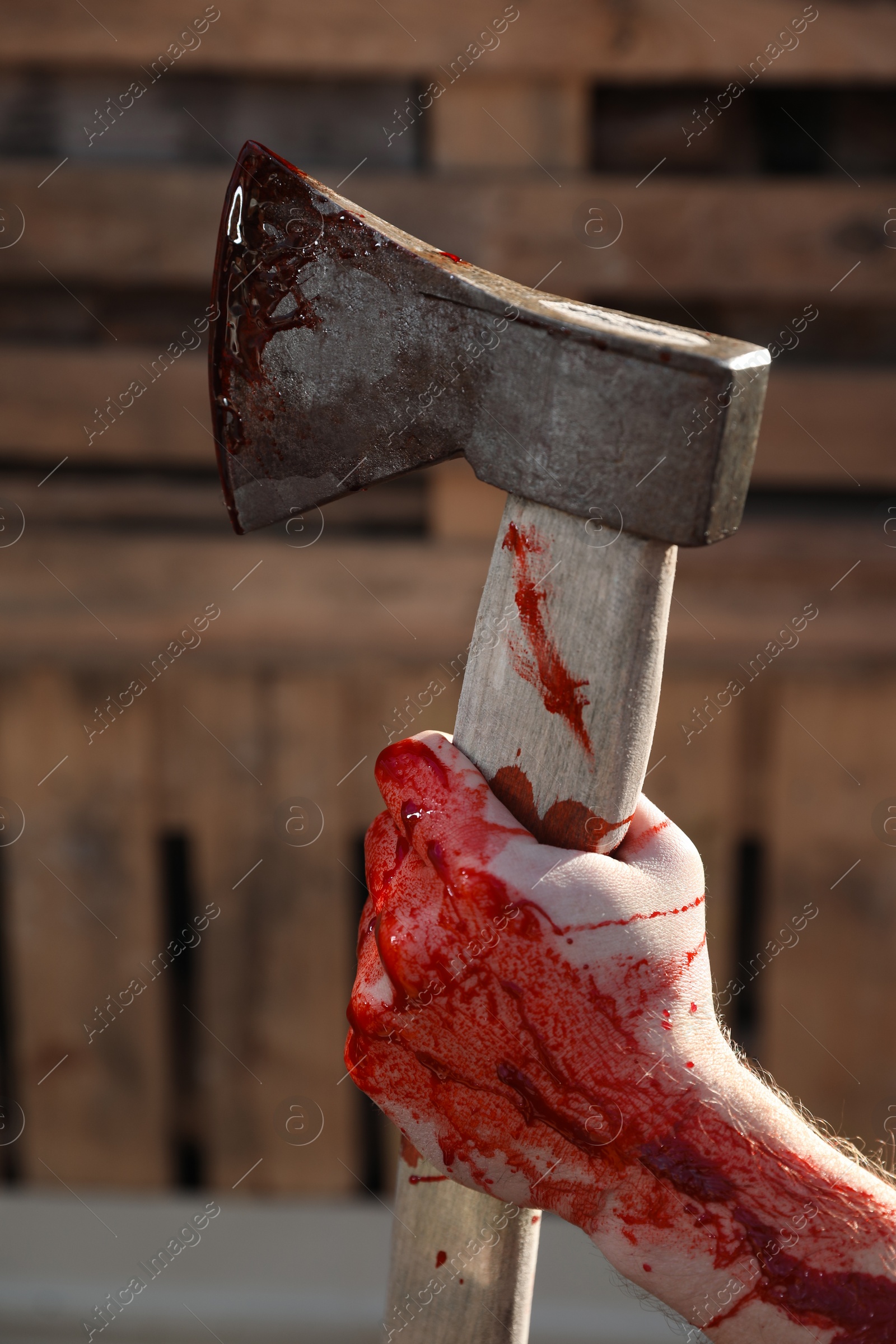 Photo of Man holding bloody axe outdoors, closeup view