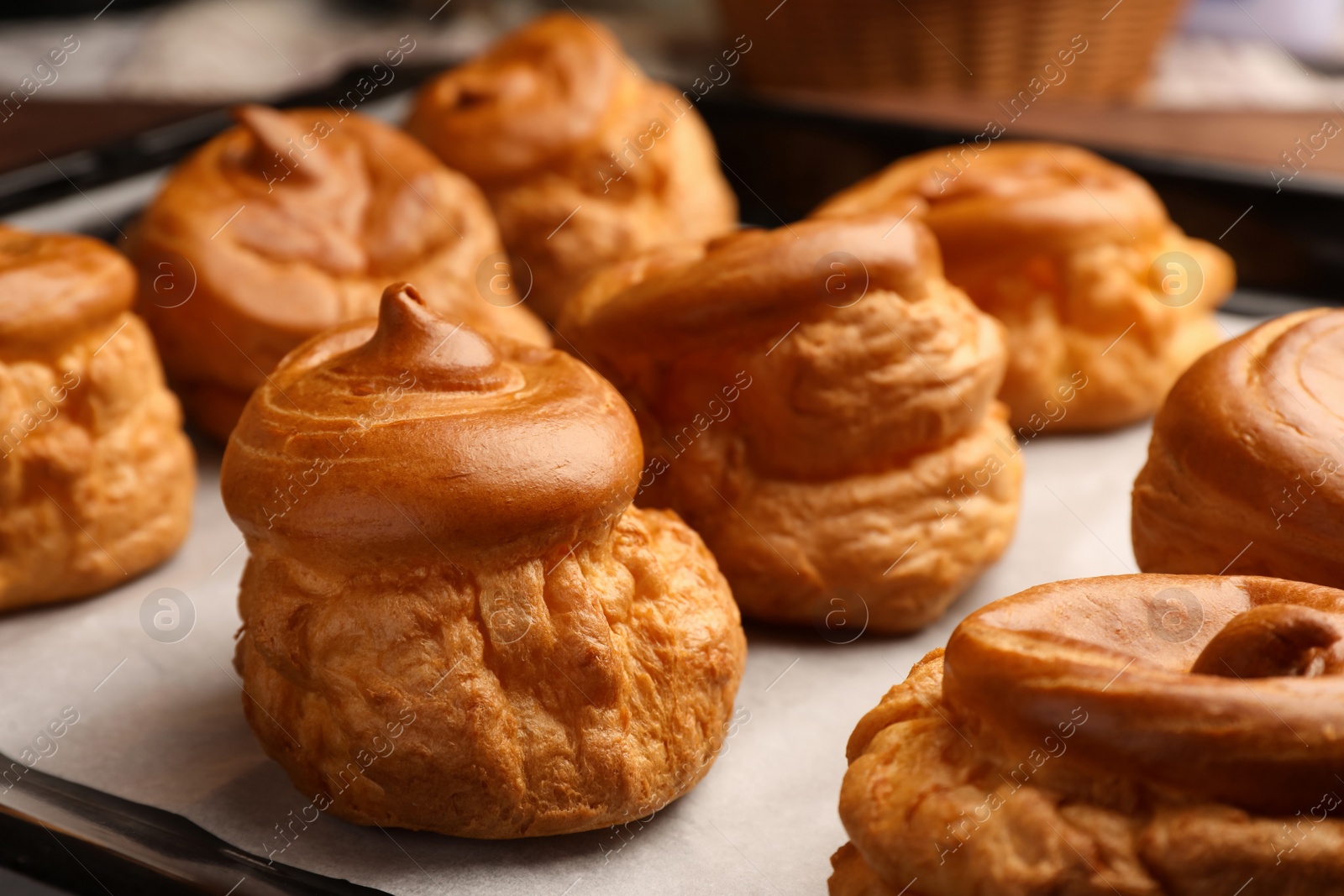 Photo of Delicious fresh profiteroles on baking pan, closeup