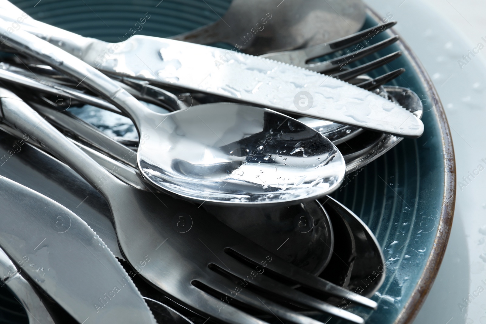 Photo of Silver clean spoons, forks and knives on plate, closeup