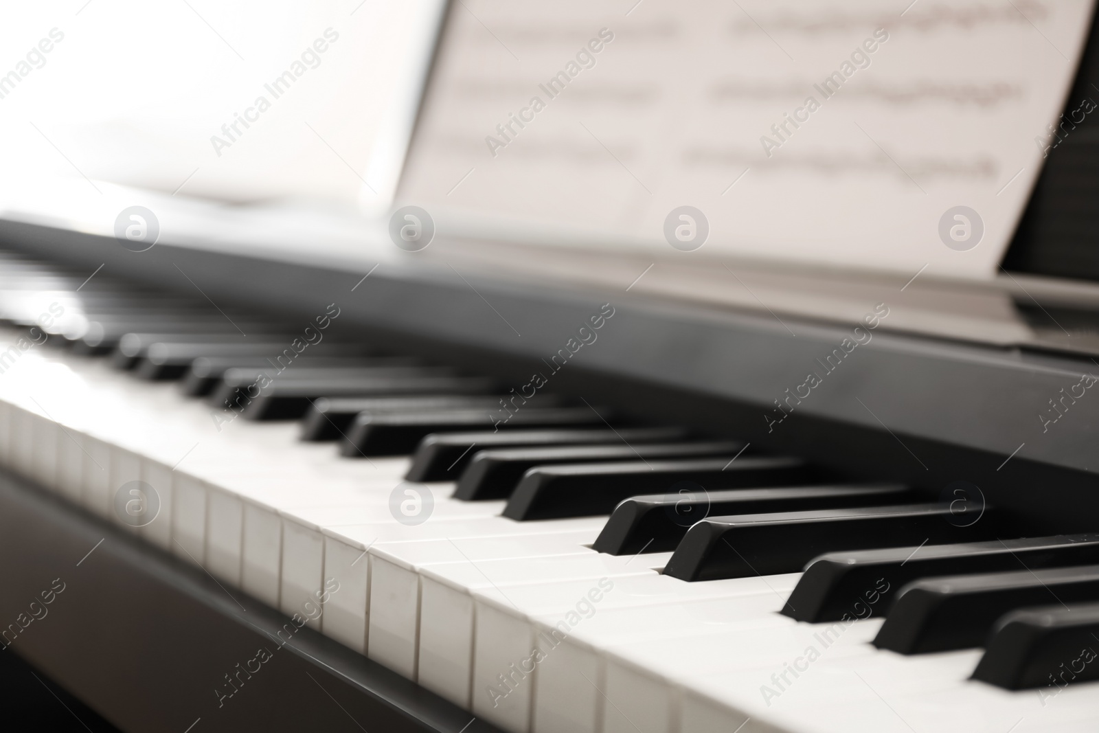 Photo of Modern piano with music sheets in room, closeup