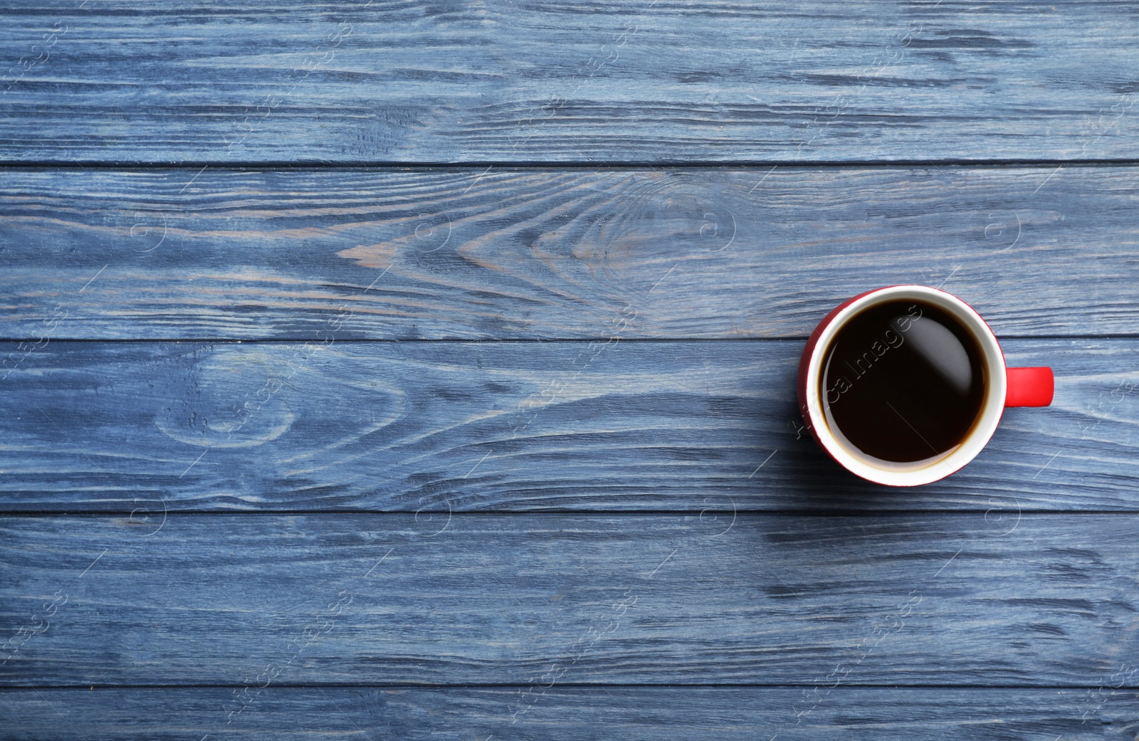 Photo of Ceramic cup with hot aromatic coffee on wooden background, top view