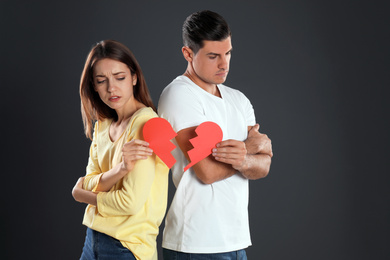 Photo of Couple with torn paper heart on black background. Relationship problems