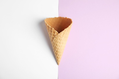 Empty wafer ice cream cone on color background, top view