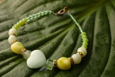 Beautiful bracelet with gemstones on green leaf, closeup