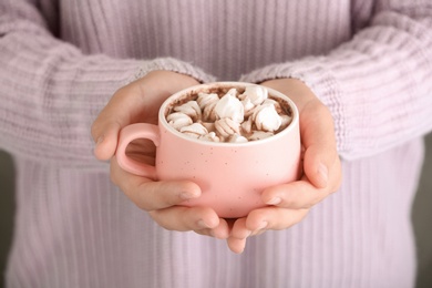 Woman holding cup of chocolate milk and marshmallows, closeup