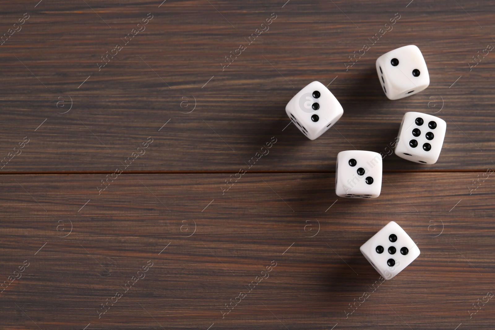 Photo of Many white game dices on wooden table, top view. Space for text