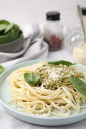 Tasty pasta with spinach, cheese and sauce on white marble table, closeup