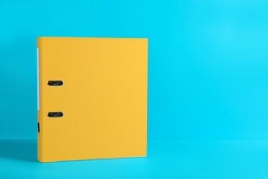Yellow office folder on light blue background, space for text