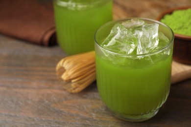 Photo of Glass of delicious iced green matcha tea on wooden table, closeup. Space for text