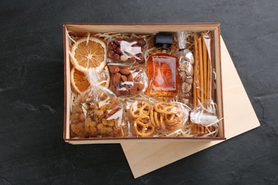 Photo of Box with stylish craft gift set on black slate table, flat lay