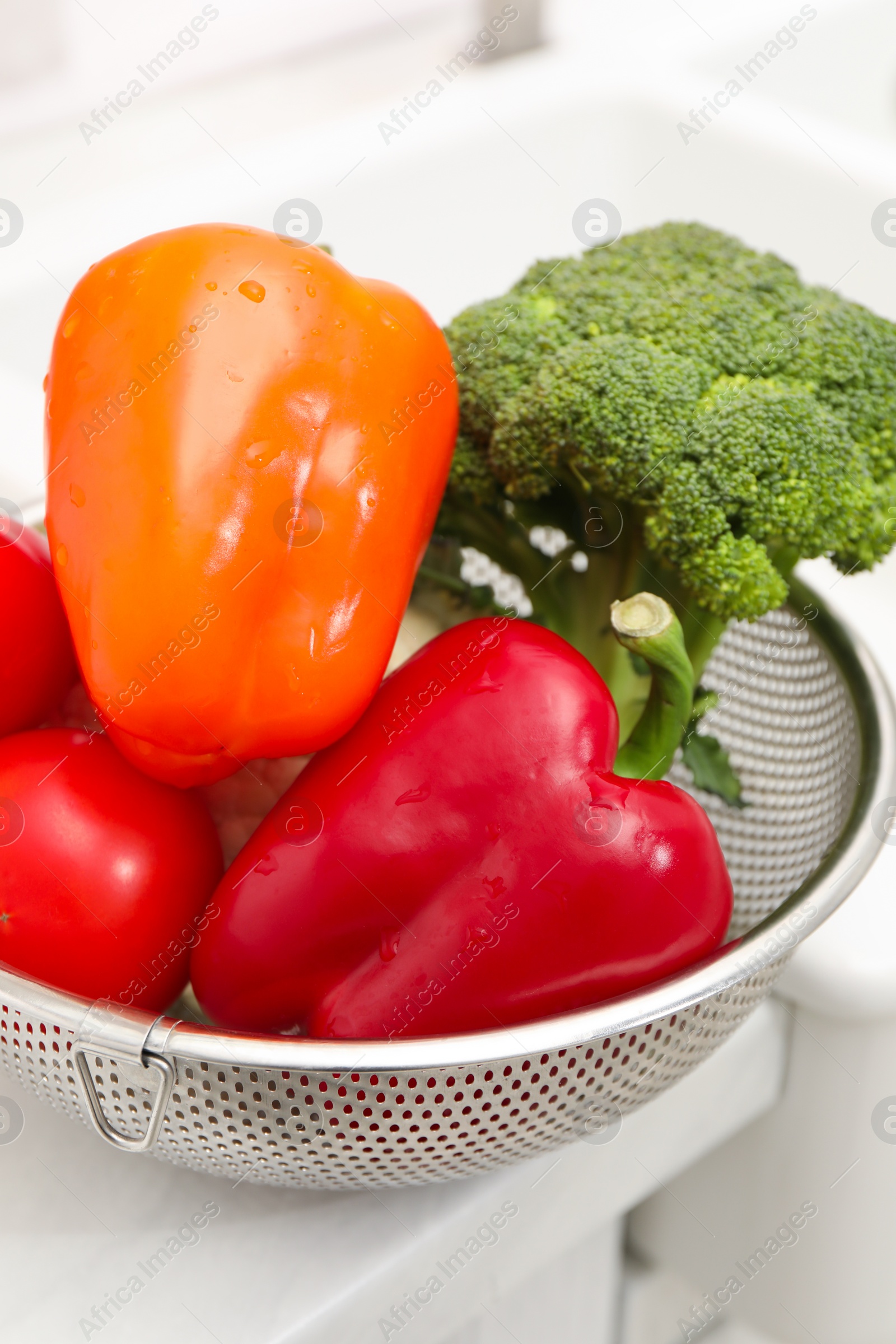 Photo of Fresh clean vegetables in colander on countertop near sink, closeup