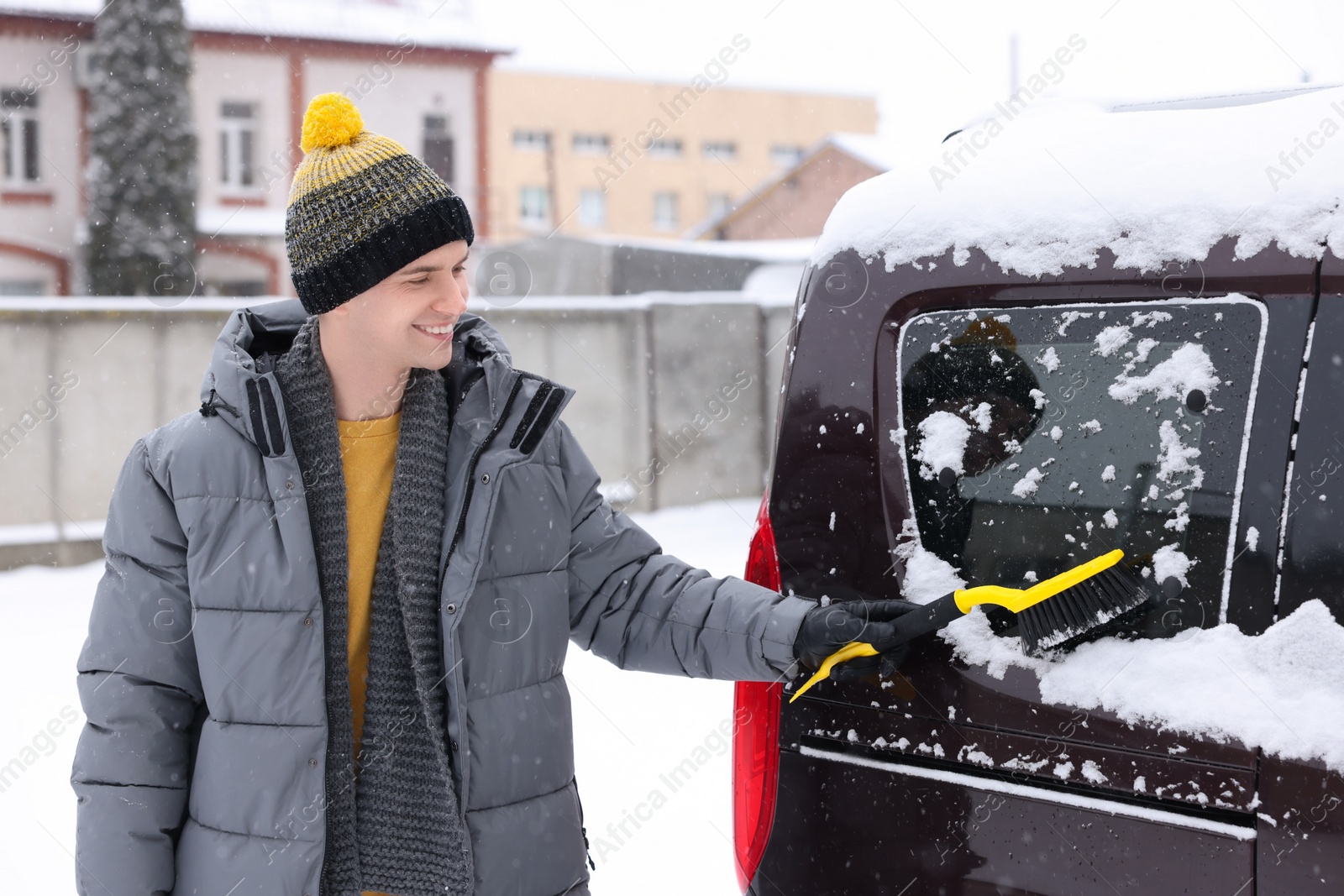 Photo of Man cleaning snow from car window outdoors