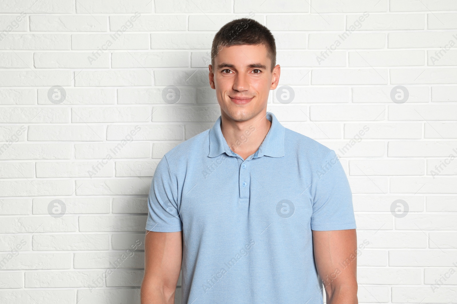 Photo of Portrait of handsome young man on white brick wall