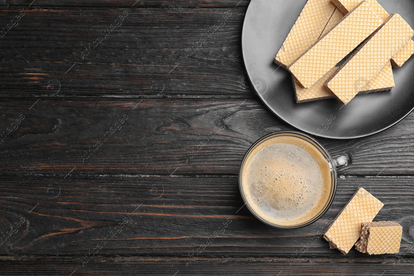 Photo of Breakfast with delicious wafers and coffee on black wooden table, flat lay. Space for text