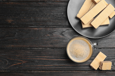 Breakfast with delicious wafers and coffee on black wooden table, flat lay. Space for text