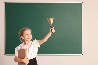 Photo of Pupil with school bell near chalkboard in classroom, space for text