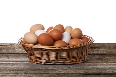Fresh chicken eggs in wicker basket on wooden table against white background