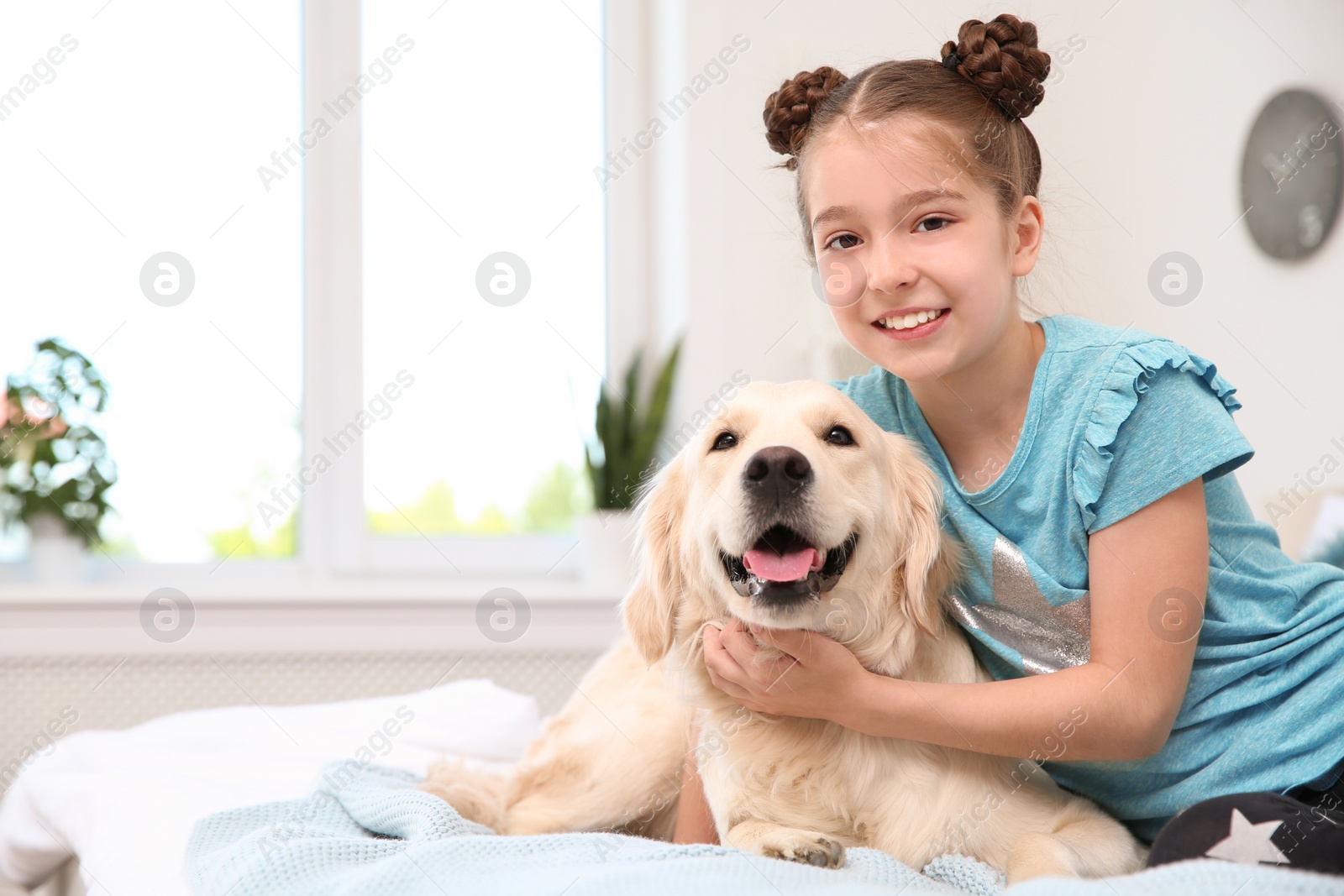 Photo of Cute little child with her pet on bed at home