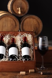 Wooden boxes, glass and wine bottles on table against black background